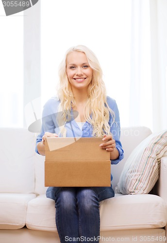 Image of smiling young woman opening cardboard box