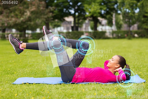 Image of smiling woman doing exercises on mat outdoors