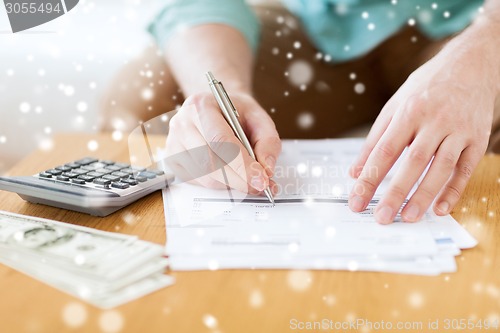 Image of close up of man counting money and making notes