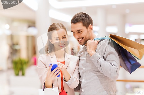 Image of couple with smartphone and shopping bags in mall