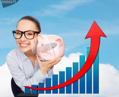 Image of happy businesswoman in eyeglasses with piggy bank