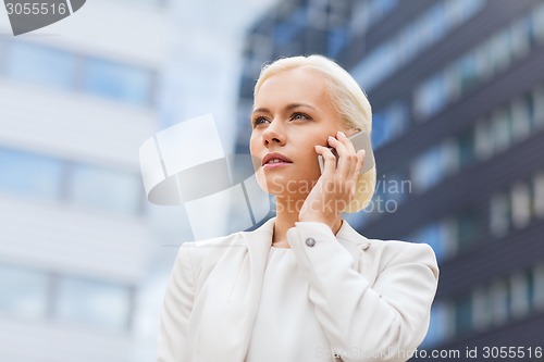 Image of serious businesswoman with smartphone outdoors