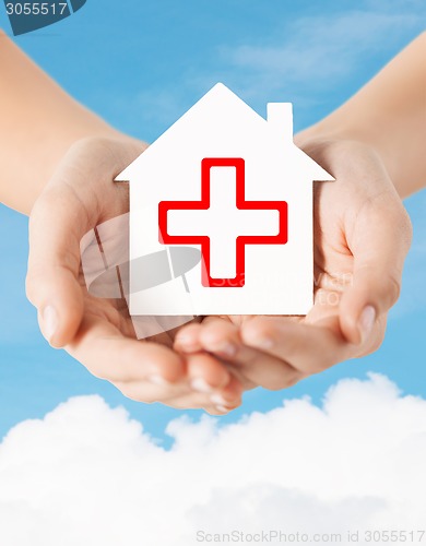 Image of hands holding paper house with red cross