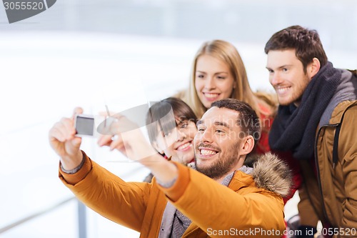 Image of happy friends with camera on skating rink