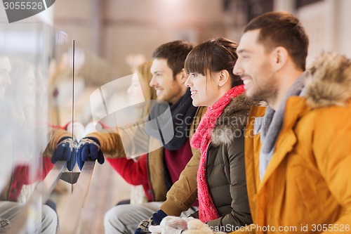 Image of happy friends watching hockey game on skating rink