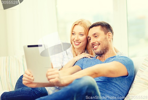 Image of smiling happy couple with tablet pc at home