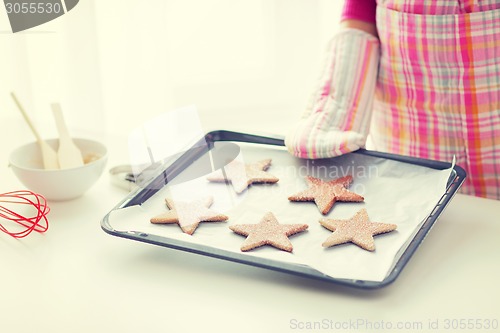 Image of close up of woman with cookies on oven tray