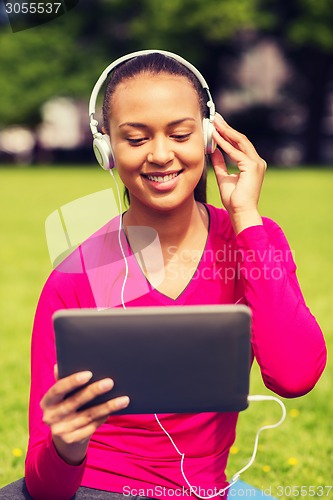 Image of smiling woman with tablet pc outdoors