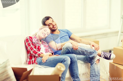 Image of smiling couple relaxing on sofa in new home