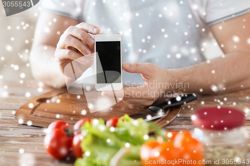 Image of closeup of man showing smartphone in kitchen