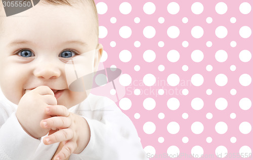 Image of smiling baby girl face over pink polka dots