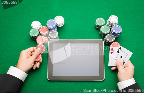 Image of casino poker player with cards, tablet and chips