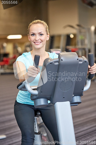 Image of smiling woman exercising on exercise bike in gym
