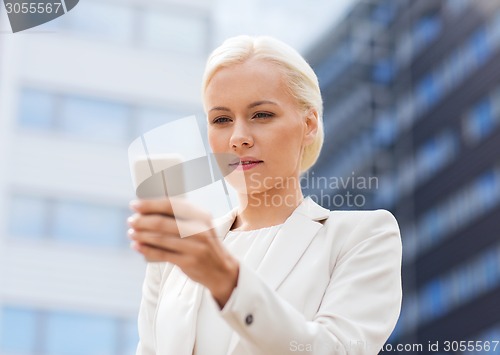 Image of serious businesswoman with smartphone outdoors
