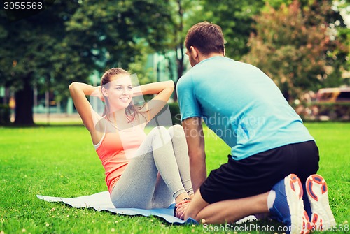 Image of smiling woman doing exercises on mat outdoors