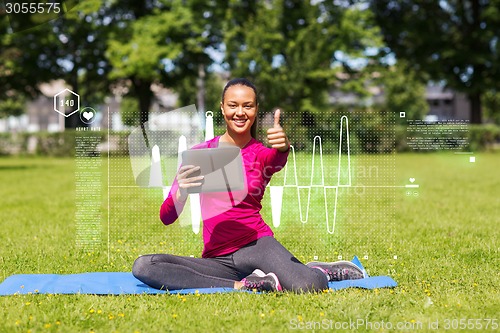 Image of smiling woman with tablet pc showing thumbs up