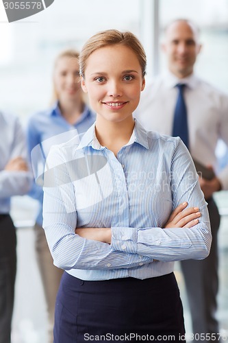Image of smiling businesswoman with colleagues in office