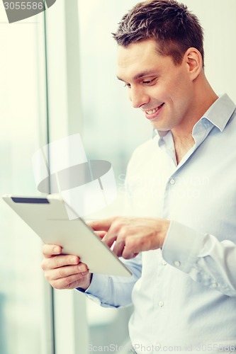 Image of smiling businessman with tablet pc in office