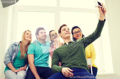 Image of five smiling students taking picture with camera