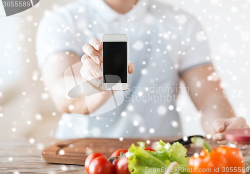 Image of close up of man showing smartphone in kitchen