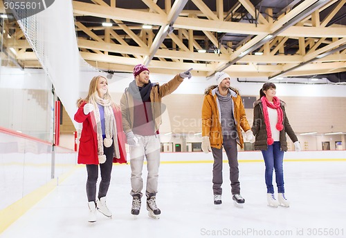 Image of happy friends pointing finger on skating rink