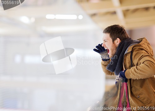 Image of young man supporting hockey game on skating rink