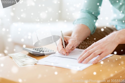 Image of close up of man counting money and making notes