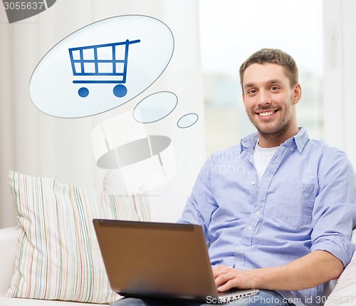 Image of smiling man with laptop shopping online at home