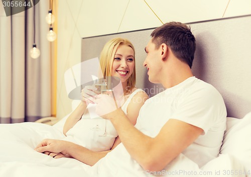 Image of smiling couple with champagne glasses in bed