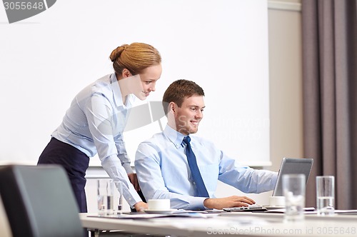 Image of businessman and secretary with laptop in office