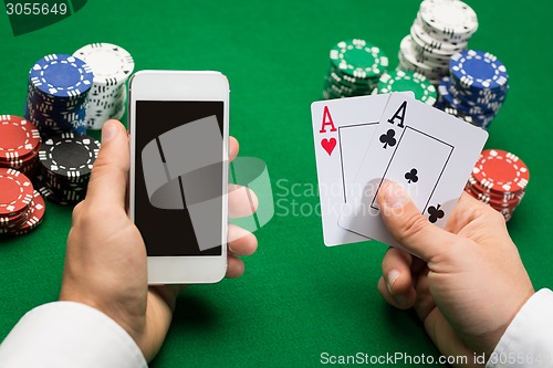 Image of casino player with cards, smartphone and chips