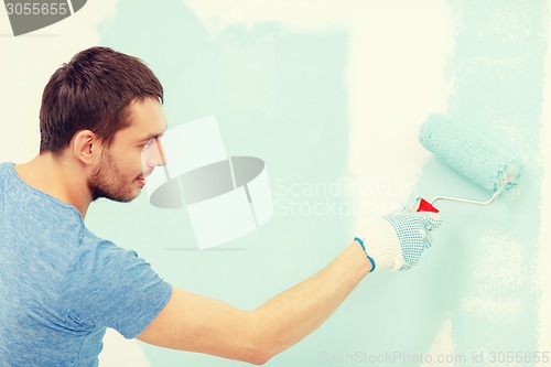 Image of smiling man painting wall at home