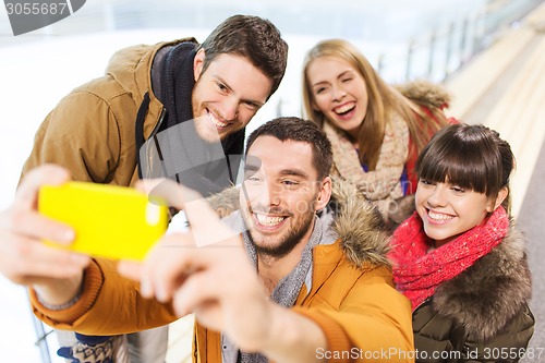 Image of happy friends with smartphone on skating rink