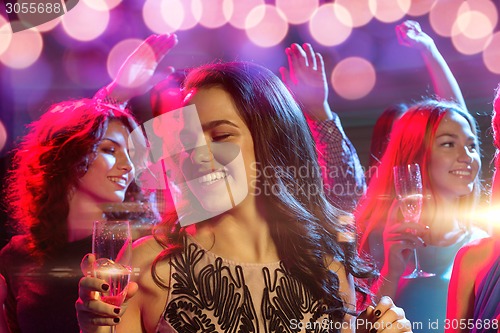 Image of smiling friends with glasses of champagne in club