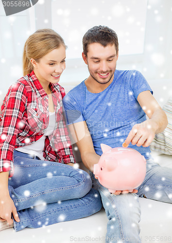 Image of smiling couple with piggybank sitting on sofa