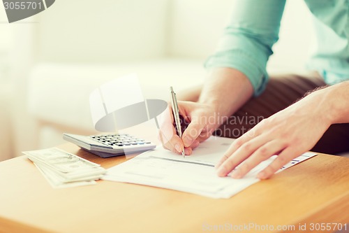 Image of close up of man counting money and making notes