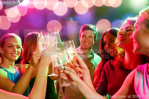 Image of smiling friends with wine glasses and beer in club