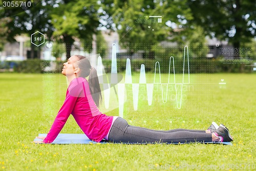 Image of smiling woman stretching back on mat outdoors