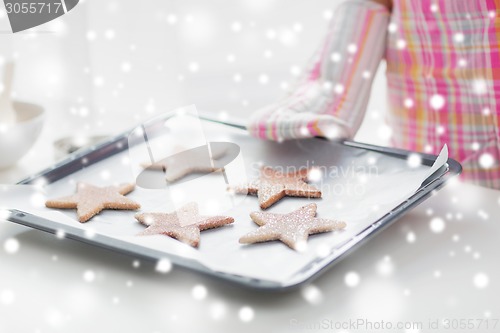 Image of close up of woman with cookies on oven tray