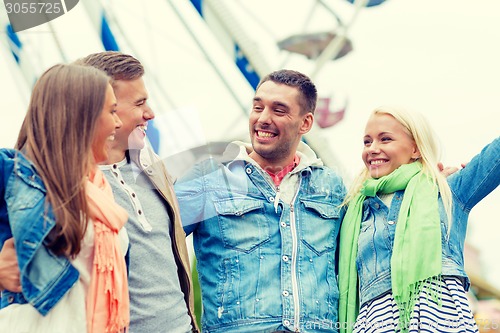 Image of group of smiling friends in amusement park