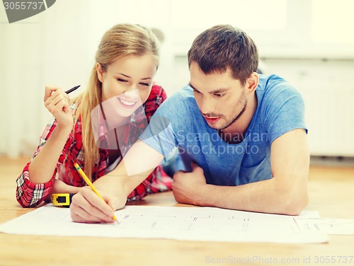 Image of smiling couple looking at blueprint at home