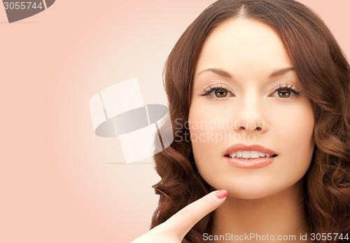 Image of beautiful young woman pointing finger to her chin