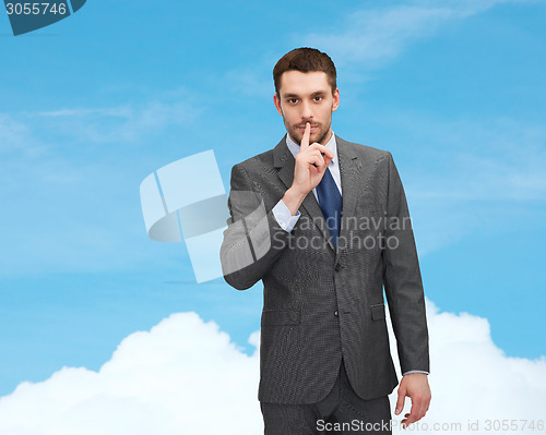 Image of young businessman making hush sign