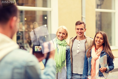 Image of group of smiling friends taking photo outdoors