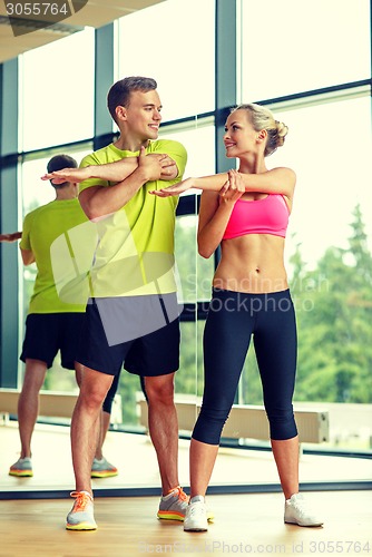 Image of smiling man and woman exercising in gym