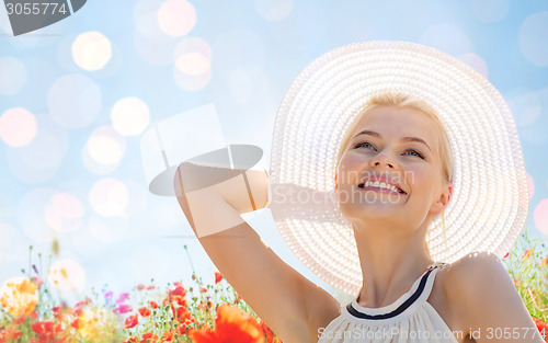 Image of smiling young woman in straw hat on poppy field