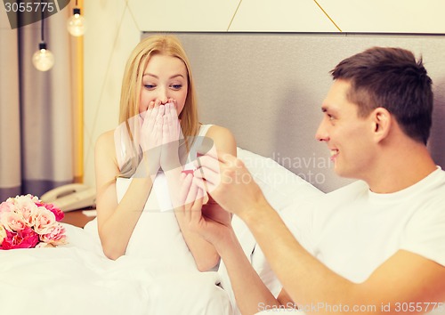 Image of man giving woman little red box and ring in it