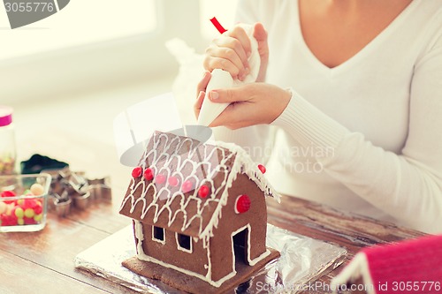 Image of close up of woman making gingerbread house at home