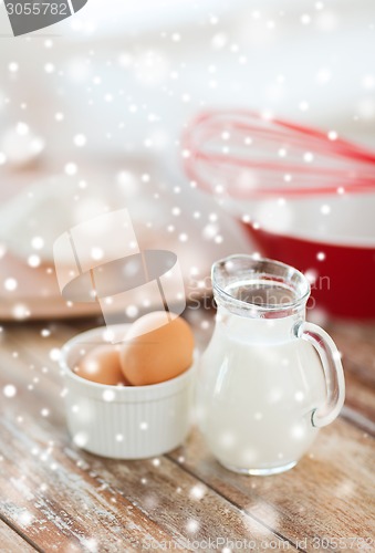 Image of close up of milk jug, eggs, whisk and flour