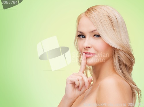 Image of beautiful young woman pointing finger to lips